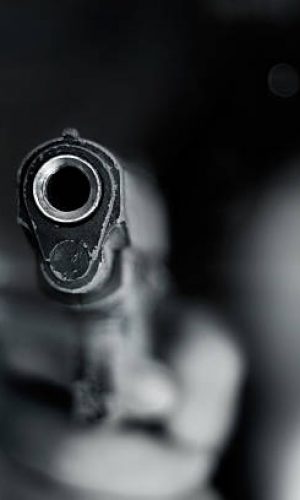 Black and white, woman pointing a old gun to front with one Hand on dark background